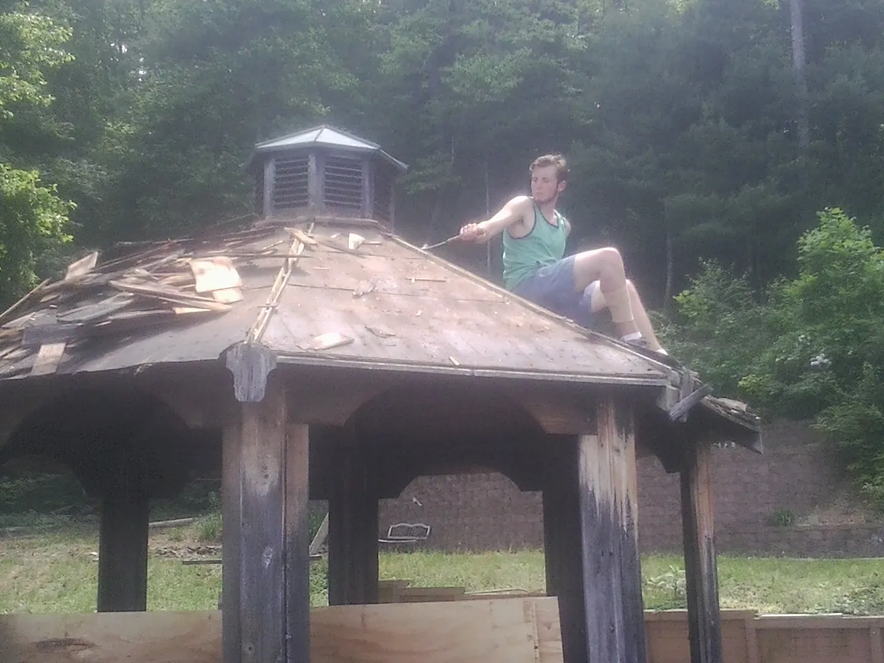 Tearing the old roof off a wooden gazebo before new shakes in Canton
