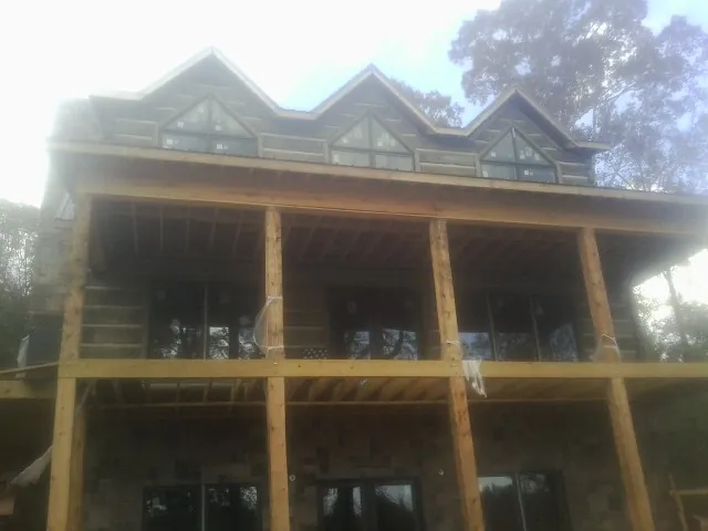 Dormers and porch framing on a large log home under construction — Roof Coating work by our crew in Canton